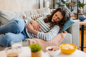 Young black woman lying on the sofa and having period cramps.